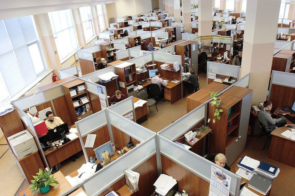 An overhead view of a conventional office floor with rows of desk